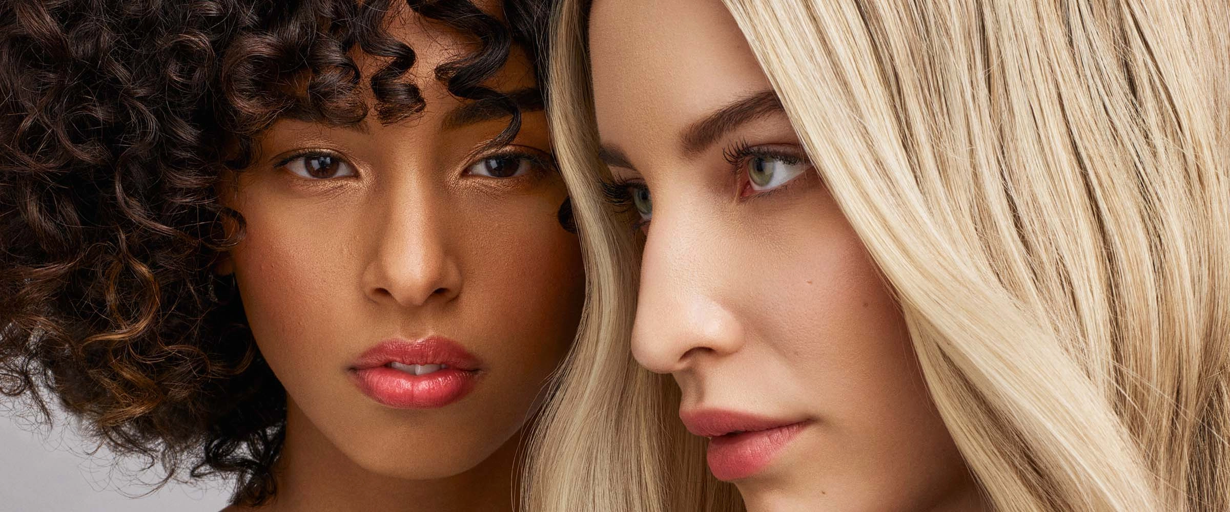 Close portrait of two women, one with dark curls and one with long blonde hair