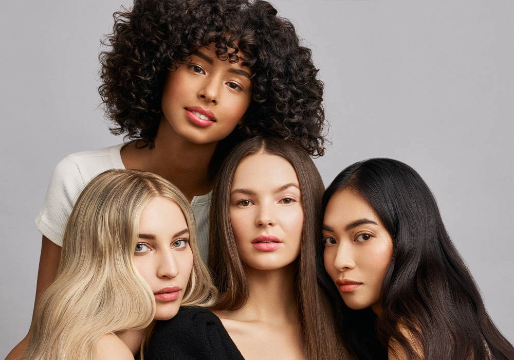 Four women with different hair colors and textures, close together