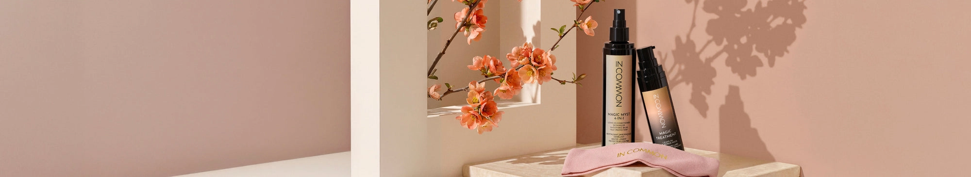Pale pink shelf with beauty products and orange flowers